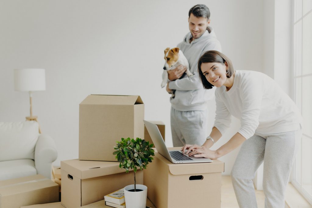 Happy home buyers pose near unpacked boxes, enjoy relocation in new house